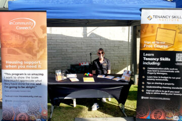 Team member sitting at inCommunity Inc stall for NAIDOC celebrations.